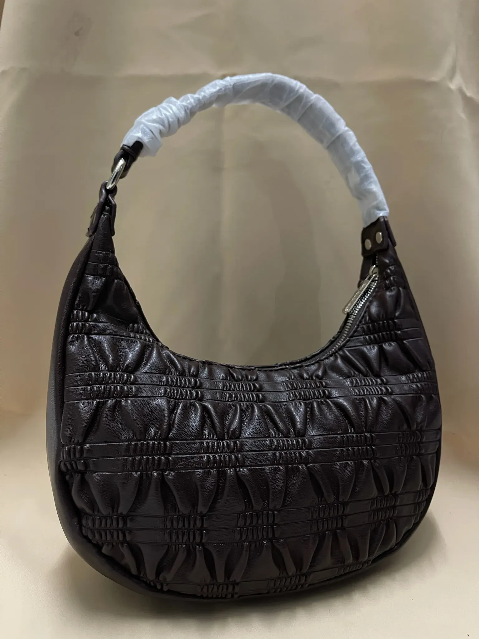 Bolsa de mano pequeña y discreta en color neutro, muy versátil.