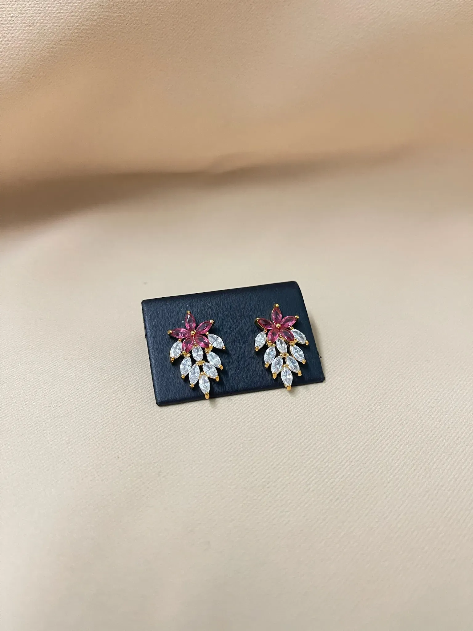 Aretes en forma de flor de Nochebuena con detalles en rojo y dorado.